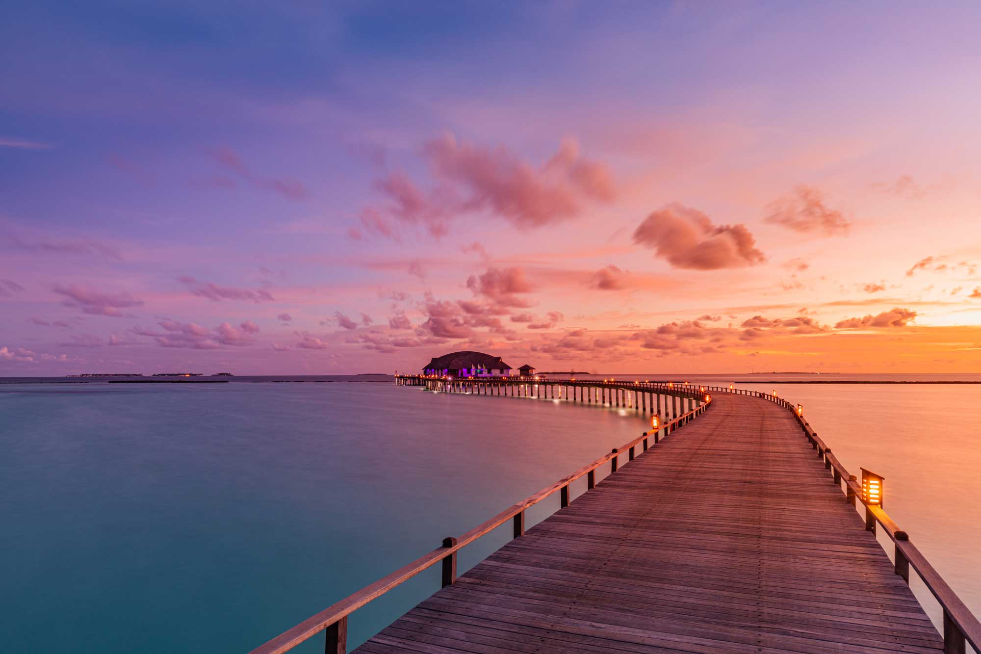 a long pier into the ocean during sunset