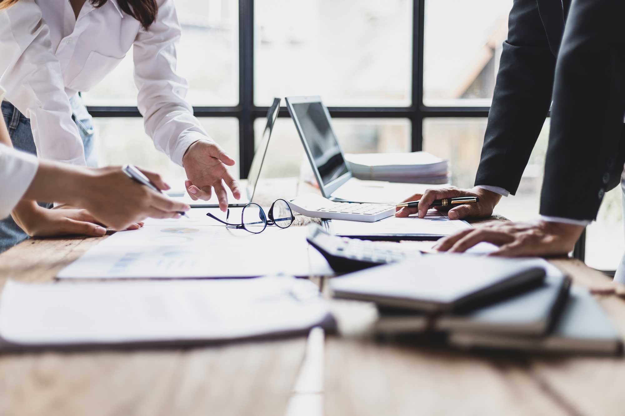 close up of professionals pointing at financial documents on a table