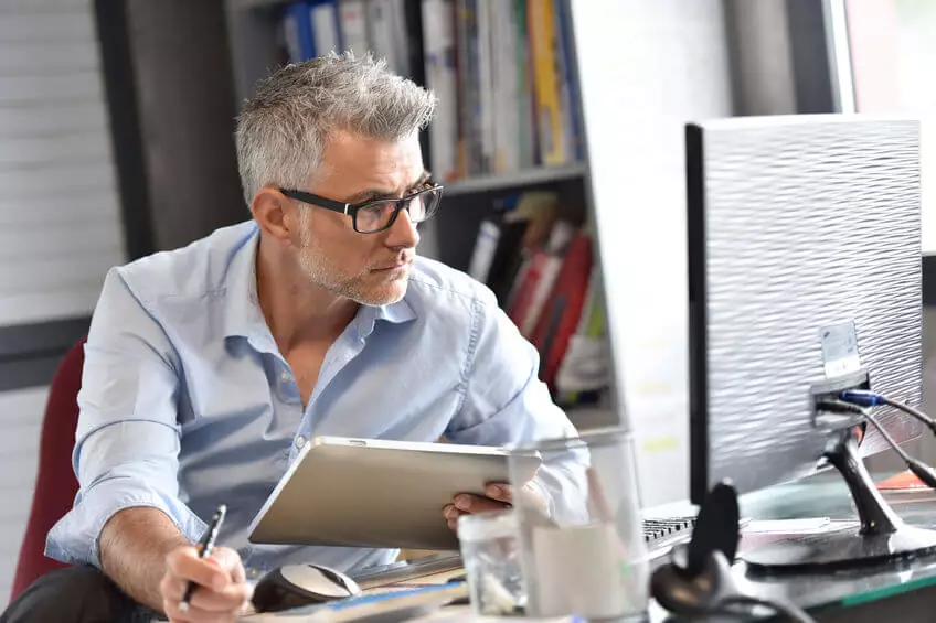 mature professional looking at data on a computer